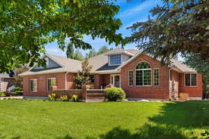 View of front facade with a front yard, brick siding, and roof with shingles