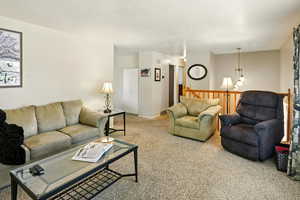 Carpeted living area featuring a textured ceiling and a chandelier
