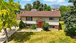 Split foyer home with brick siding, a front lawn, a mountain view, a shingled roof, and driveway
