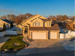 View of front of home with concrete driveway, a garage, stucco siding, roof with shingles, and brick siding
