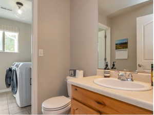 Bathroom featuring washer and dryer, vanity, and tile patterned floors