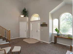 Carpeted foyer featuring healthy amount of natural light, stairway, and high vaulted ceiling