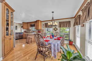 Dining room featuring light wood-style flooring, plenty of natural light, crown molding, a chandelier, and recessed lighting