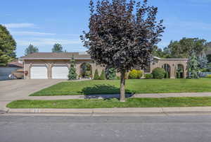 View of front of property with a front yard, driveway, brick siding, and an attached garage
