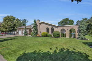 View of front of property featuring a front yard, concrete driveway, brick siding, and a garage