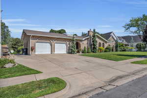 View of front of home with an attached garage, driveway, a front lawn, and brick siding