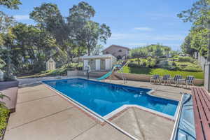 Outdoor pool with a patio area and a water slide, diving board