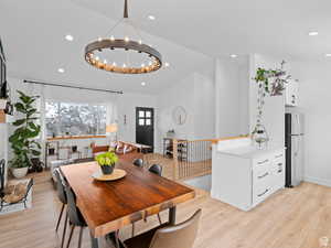 Dining area with light wood finished floors, a chandelier, and recessed lighting