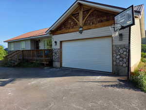 Front view of home with asphalt driveway, stone siding, an attached large 2 car garage, and a metal roof!