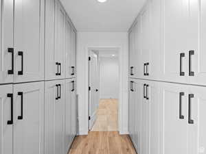 Hall featuring ample cabinets for storage. Laundry room and garage entrance further ahead.