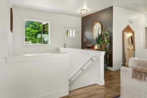Hall with an upstairs landing and dark wood-style flooring