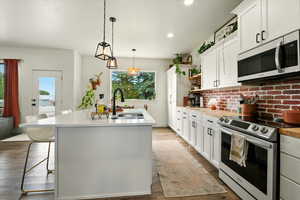 Kitchen with electric stove, plenty of natural light, open shelves, an island with sink, and recessed lighting