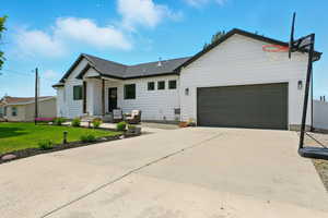 View of front of property featuring an attached garage, a front lawn, driveway, and an outdoor living space