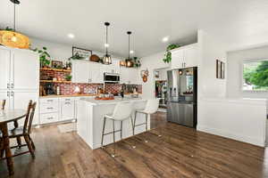 Kitchen with stainless steel appliances, light countertops, open shelves, dark wood finished floors, and recessed lighting