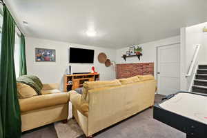 Living area with carpet, stairway, and brick wall
