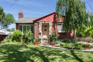 View of front of home with brick siding, a front yard, a chimney, and entry steps