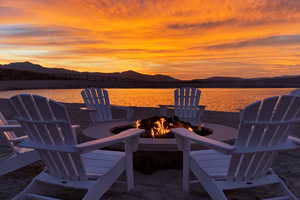 Patio terrace at dusk featuring an outdoor fire pit and a water and mountain view
