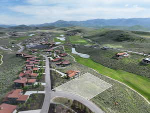 Aerial overview of property's location featuring a water and mountain view, property parcel outlined, and nearby suburban area