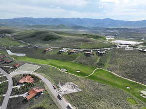 Aerial view of property and surrounding area featuring a water and mountain view and a local golf course