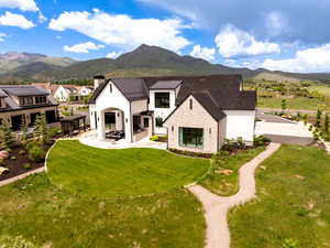 Rear view of property with a mountain view, a chimney, a yard, and a patio area