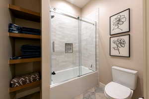 Full bath with enclosed tub / shower combo and tile patterned floors