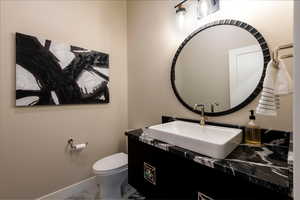 Half bathroom with marble look tile flooring and vanity