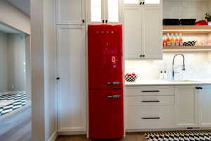 Kitchen featuring refrigerator, white cabinets, light countertops, and backsplash