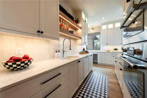 Kitchen with white cabinetry, light stone countertops, stainless steel double oven, tasteful backsplash, and recessed lighting