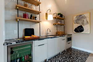 Indoor bar with beverage cooler, vaulted ceiling, and stainless steel microwave
