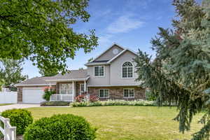 Split level home featuring stone siding, an attached garage, concrete driveway, stucco siding, and a porch