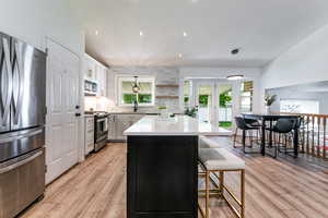 Kitchen featuring stainless steel appliances, light wood-type flooring, a kitchen island, french doors, and healthy amount of natural light