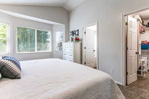 Bedroom with a spacious closet, carpet flooring, vaulted ceiling, and a closet