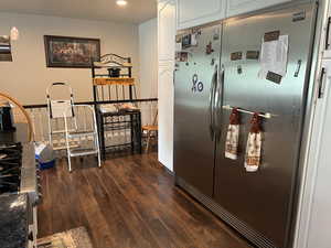 Kitchen featuring freestanding refrigerator, dark wood finished floors, recessed lighting, dark countertops, and white cabinetry