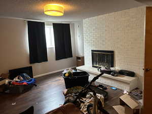 Office area featuring hardwood / wood-style flooring, a textured ceiling, baseboards, and a brick fireplace