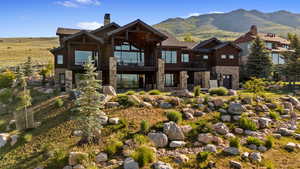 View of front of house featuring stone siding, a balcony, a chimney, and a mountain view
