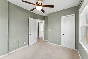 Unfurnished bedroom featuring light carpet, a closet, and ceiling fan