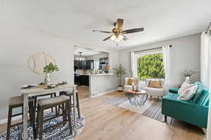 Living room with light wood finished floors, ceiling fan, and a textured ceiling