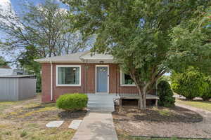 Bungalow featuring brick siding, roof with shingles, and an outbuilding