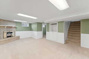 Basement with carpet, stairs, wainscoting, and a fireplace
