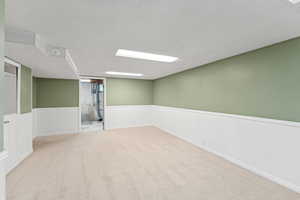 Carpeted empty room featuring a wainscoted wall