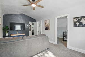 Living room with a ceiling fan, lofted ceiling, and carpet floors