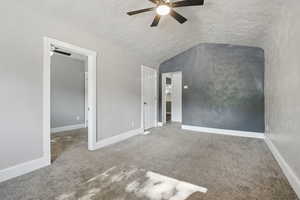 Unfurnished bedroom featuring carpet, lofted ceiling, a textured ceiling, and ceiling fan