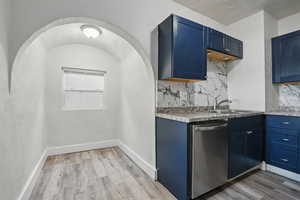 Kitchen featuring stainless steel dishwasher, blue cabinetry, and light wood-type flooring