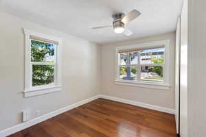 Unfurnished room with dark wood-style floors and ceiling fan