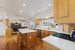 Kitchen with stainless steel dishwasher, a ceiling fan, a kitchen island, a breakfast bar area, and crown molding