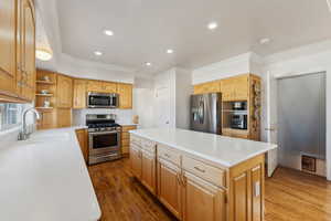 Kitchen with stainless steel appliances, crown molding, a kitchen island, wood finished floors, and open shelves