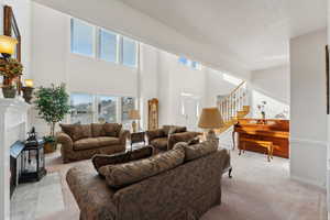 Living room featuring light colored carpet, stairs, and a high ceiling