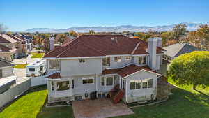 Back of property with a chimney, stucco siding, a mountain view, a tile roof, and a residential view