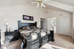 Bedroom with light colored carpet, high vaulted ceiling, ensuite bath, and ceiling fan