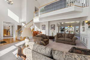 Living room with a chandelier, a towering ceiling, stairs, and carpet floors